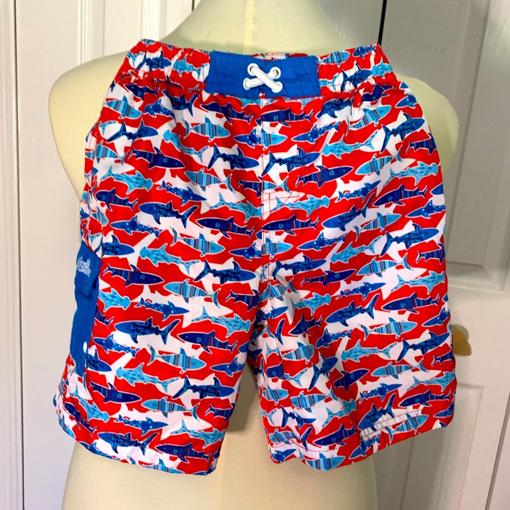 Shark print red and blue UV Skins boys swim trunks.